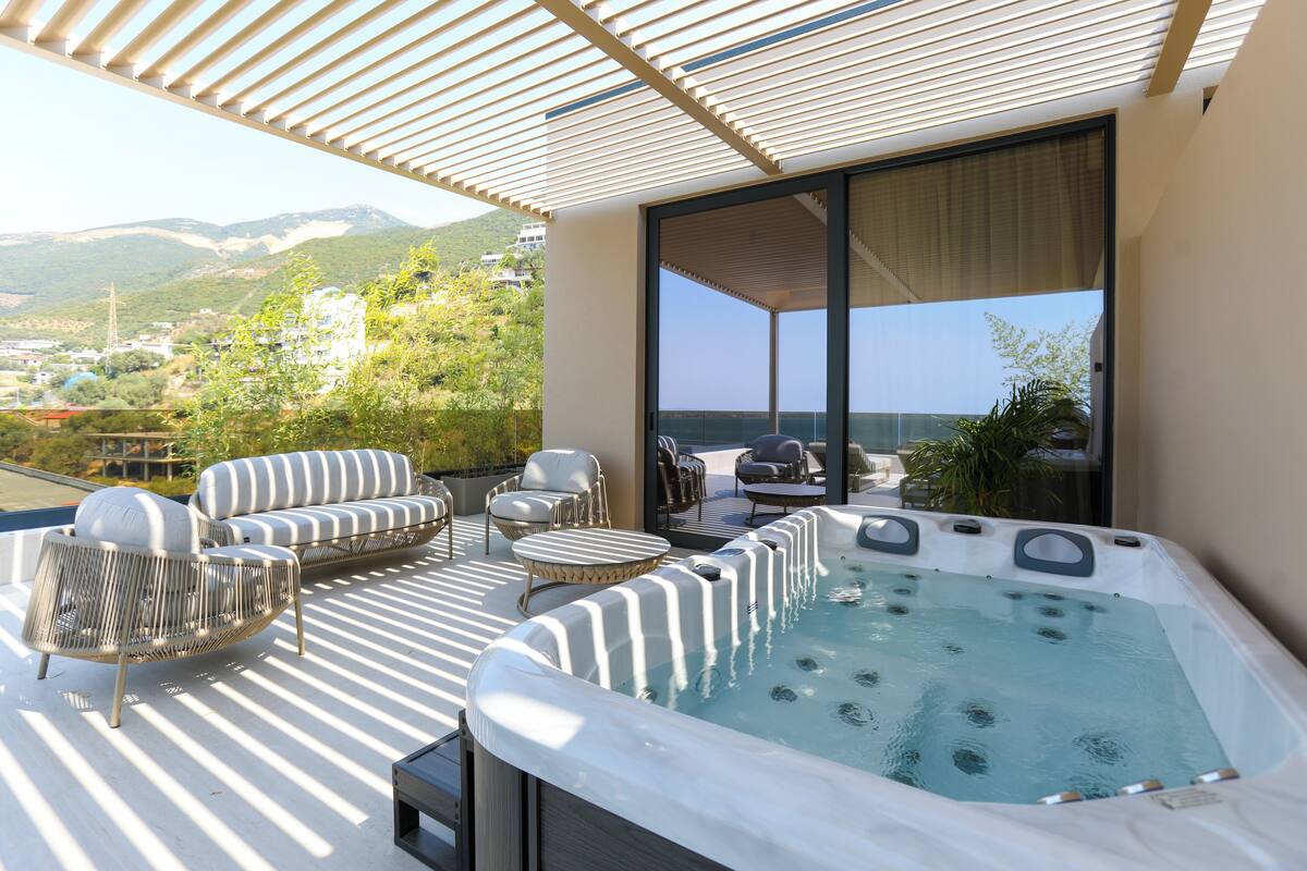 Una terraza en la azotea con hidromasaje, asientos al aire libre y vistas del paisaje.