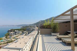 A rooftop terrace with seating, a view of the sea, and buildings in the background. - Sol Boutique Hotel (Vlorë)