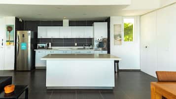 A modern kitchen with a central island, stainless steel appliances, and dark flooring.