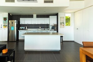 A modern kitchen with a central island, stainless steel appliances, and dark flooring.