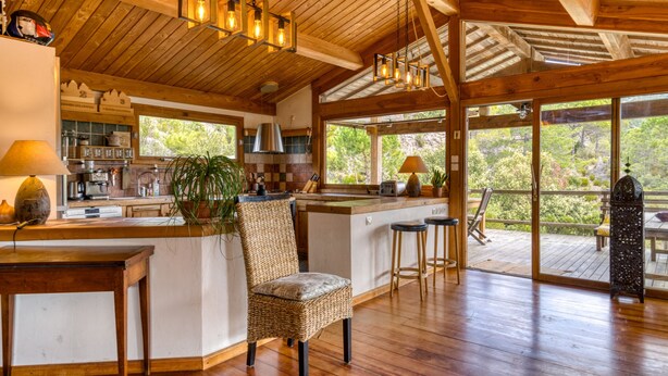A spacious kitchen with wooden beams, a large island, and a view of the outdoors. - Family Villa in Exceptional Setting with Mountain View, Wi-Fi, and Air Conditioning (Mourèze)