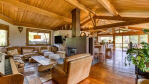 A spacious living area with a fireplace, wooden furniture, and large windows. - Family Villa in Exceptional Setting with Mountain View, Wi-Fi, and Air Conditioning (Mourèze)