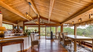 A spacious kitchen with wooden beams, a dining area with chairs and a table, and large windows offering a view of the outdoors. - Family Villa in Exceptional Setting with Mountain View, Wi-Fi, and Air Conditioning (Mourèze)