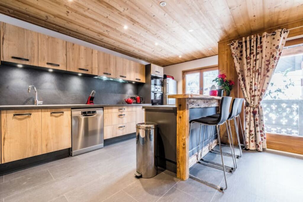 A modern kitchen with wooden cabinets, stainless steel appliances, and a bar area with bar stools.