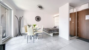 A modern, compact bedroom with a bed, bedside table, and a small dining area with chairs and a table. - Sun & Snow Odrzanskie Bulvary (Szczecin)
