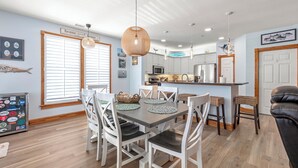 Une cuisine moderne avec des meubles blancs, un îlot central et des luminaires suspendus.