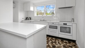 Una cocina moderna con armarios blancos, una isla grande, una ventana y un salpicadero de azulejos.