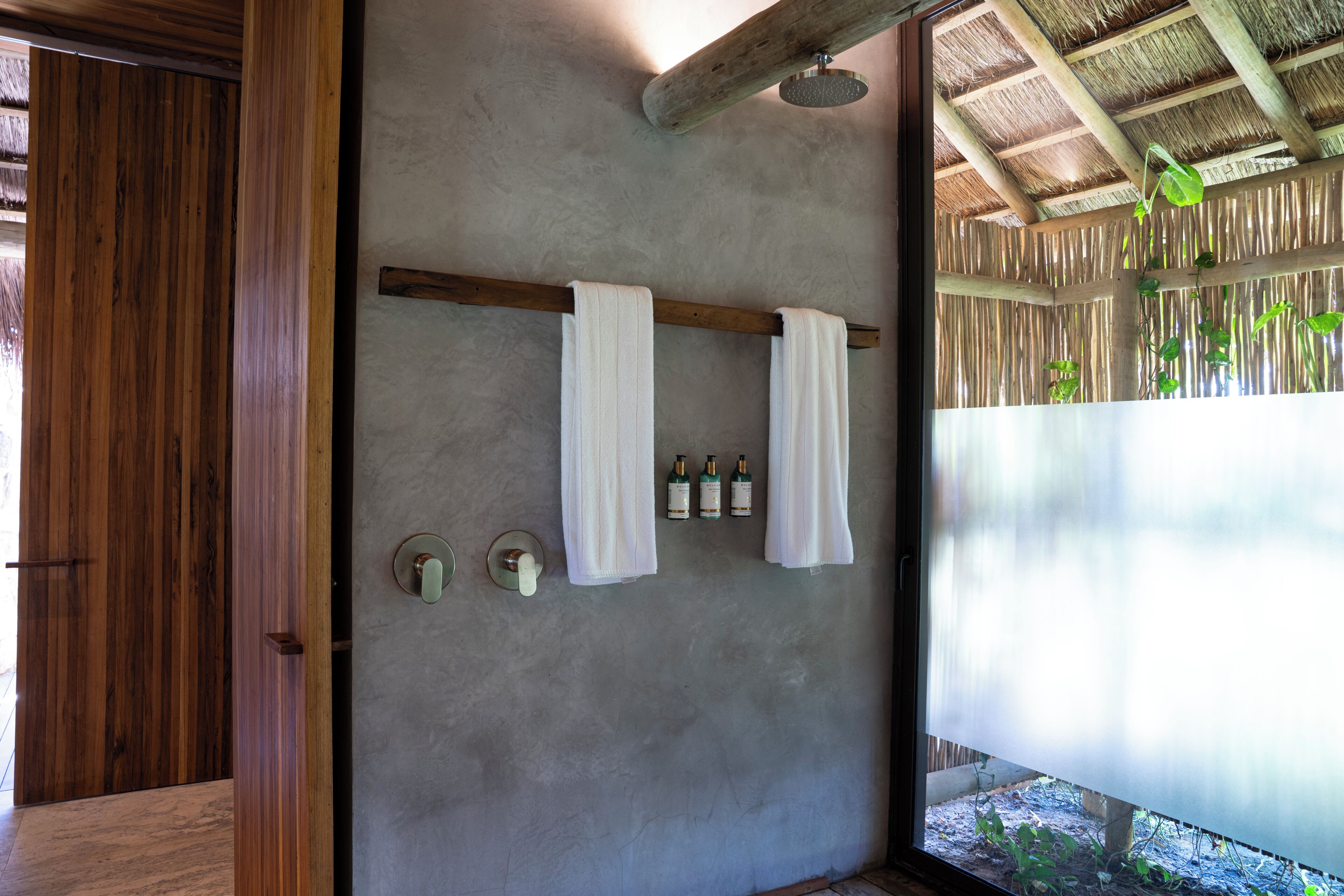 A bathroom with wooden doors, a towel rack with two towels, and a shower area with a wooden ceiling.