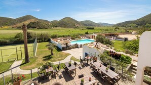 Area piscina con vista sulle colline, posti a sedere all'aperto e un campo da tennis.