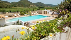 Area piscina con sedie a sdraio e vista sulle colline verdi.
