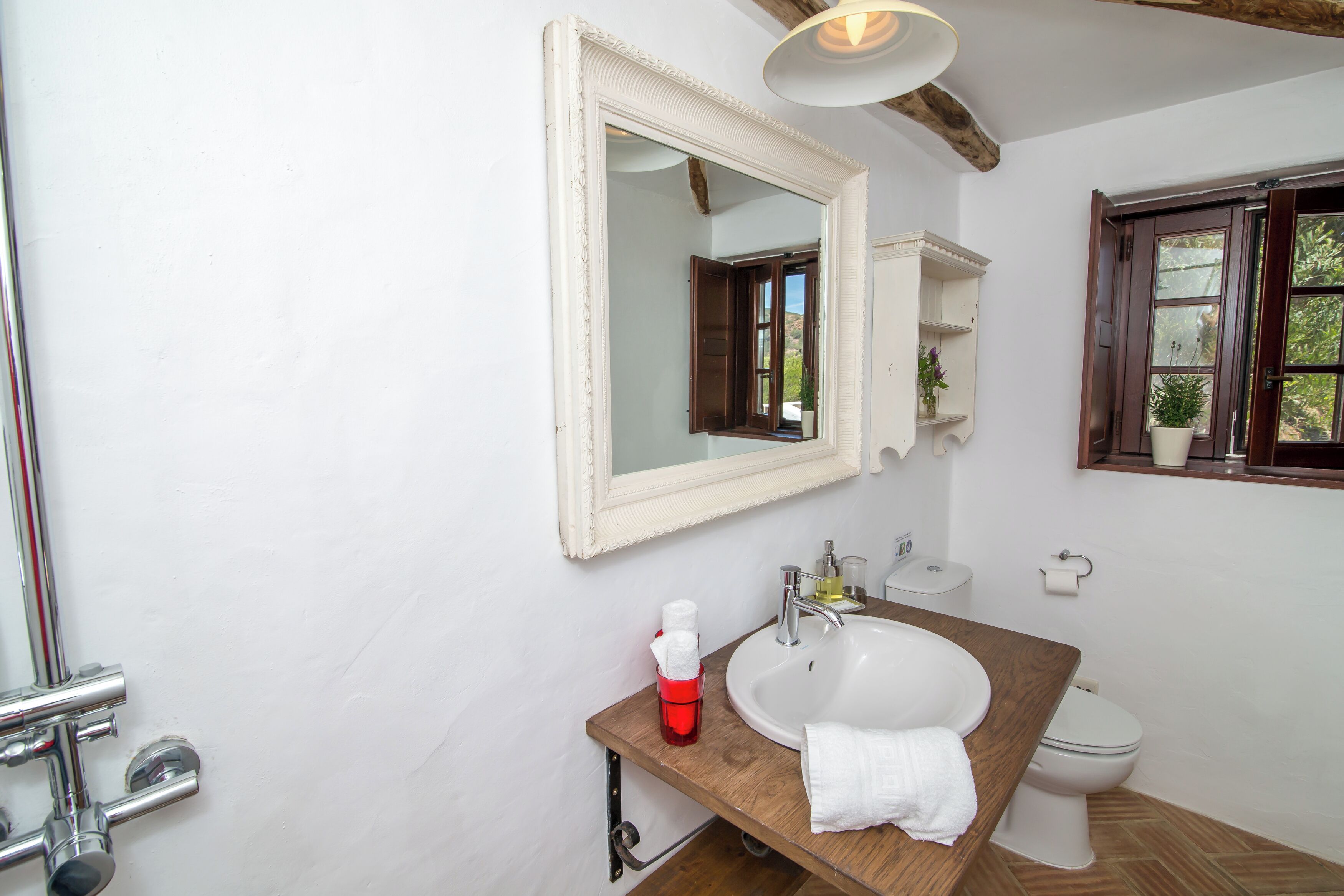 A bathroom with a white sink, a mirror, a wooden countertop, a towel, and a toilet.