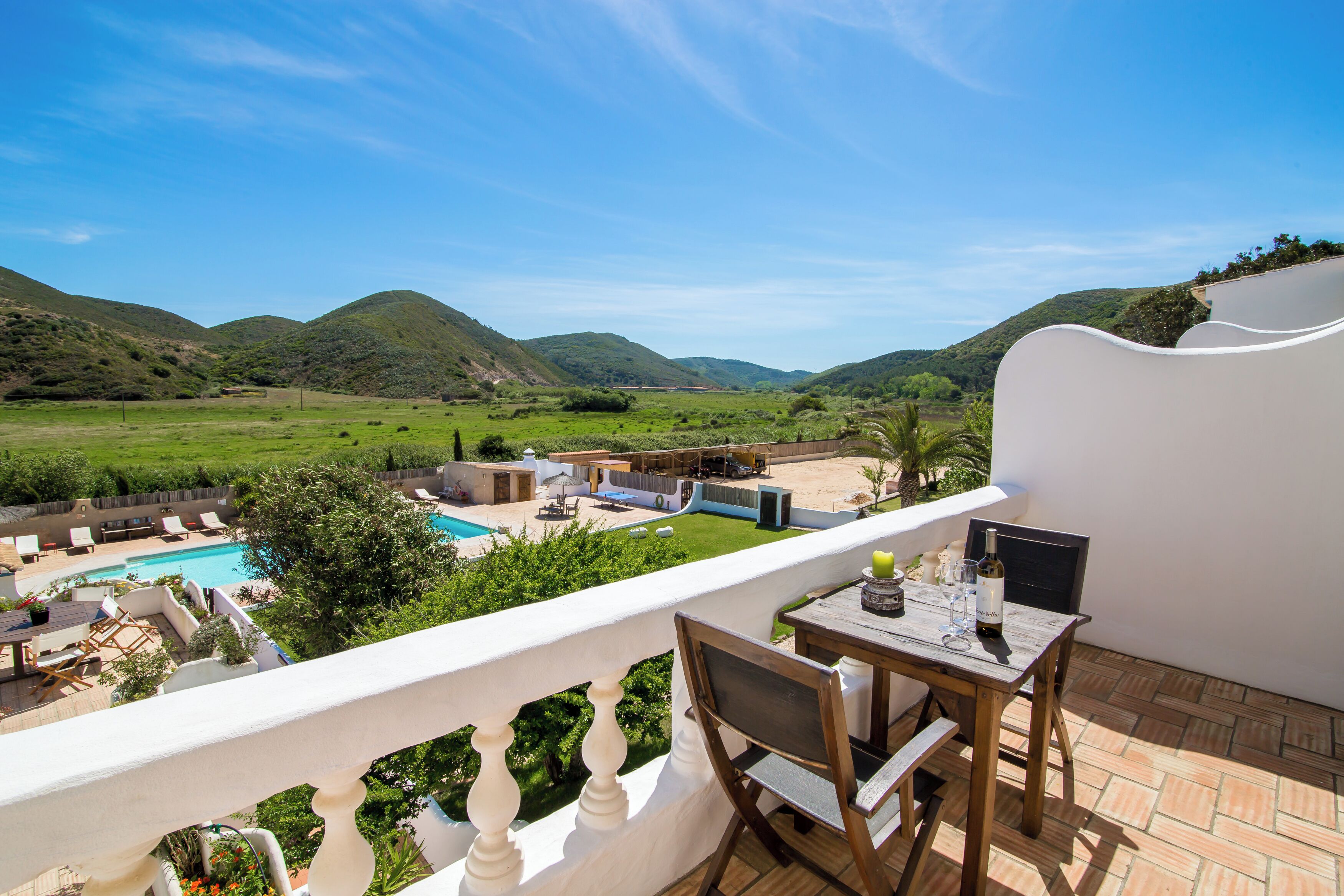 Un balcón con vistas a una piscina y colinas.