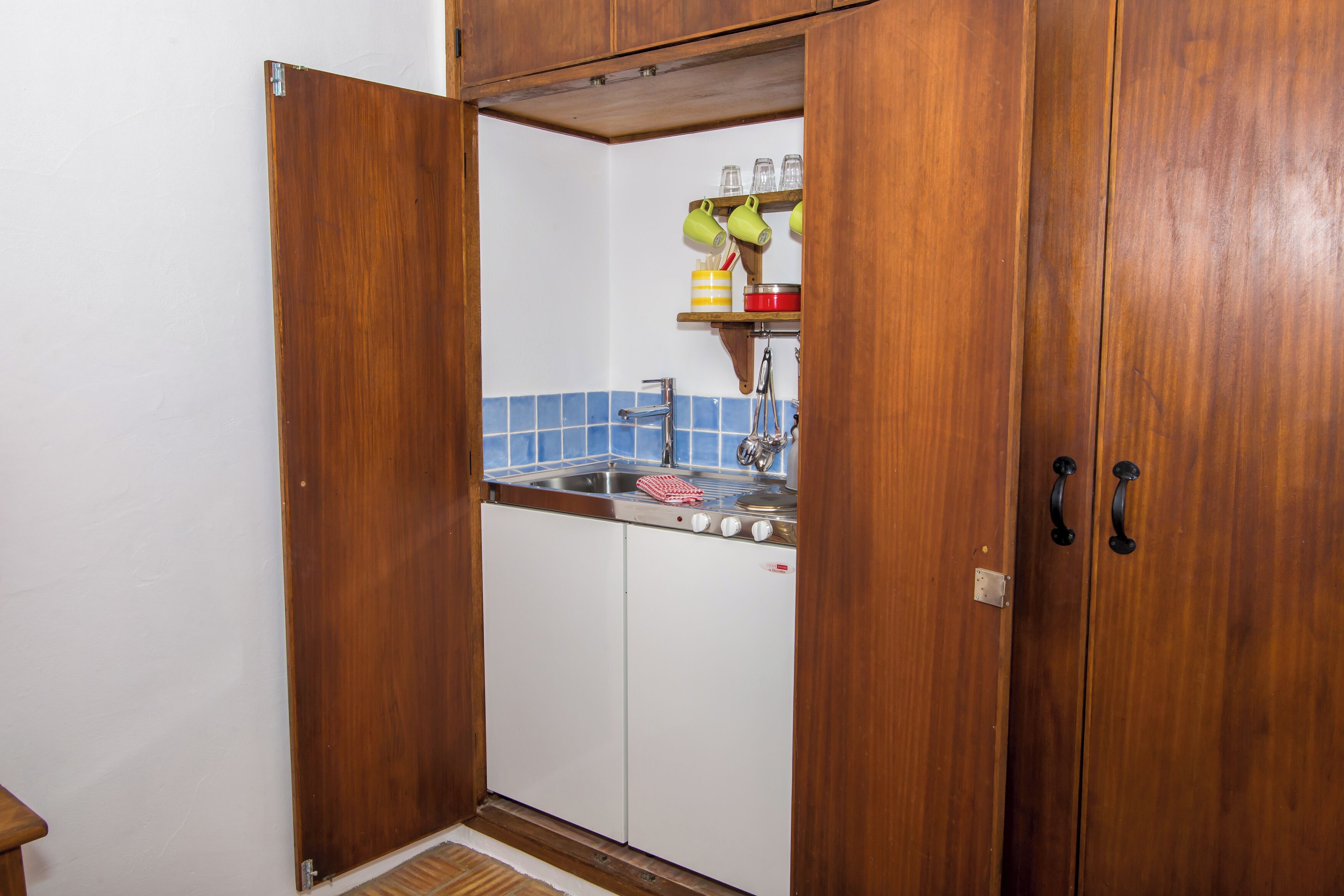 Una cocina compacta con armarios de madera, un lavamanos y un salpicadero de azulejos.