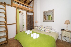 A bedroom with a green bedspread, a wooden ladder, a mirror, a bedside lamp, and a telephone. - Casa Fajara (Aljezur)