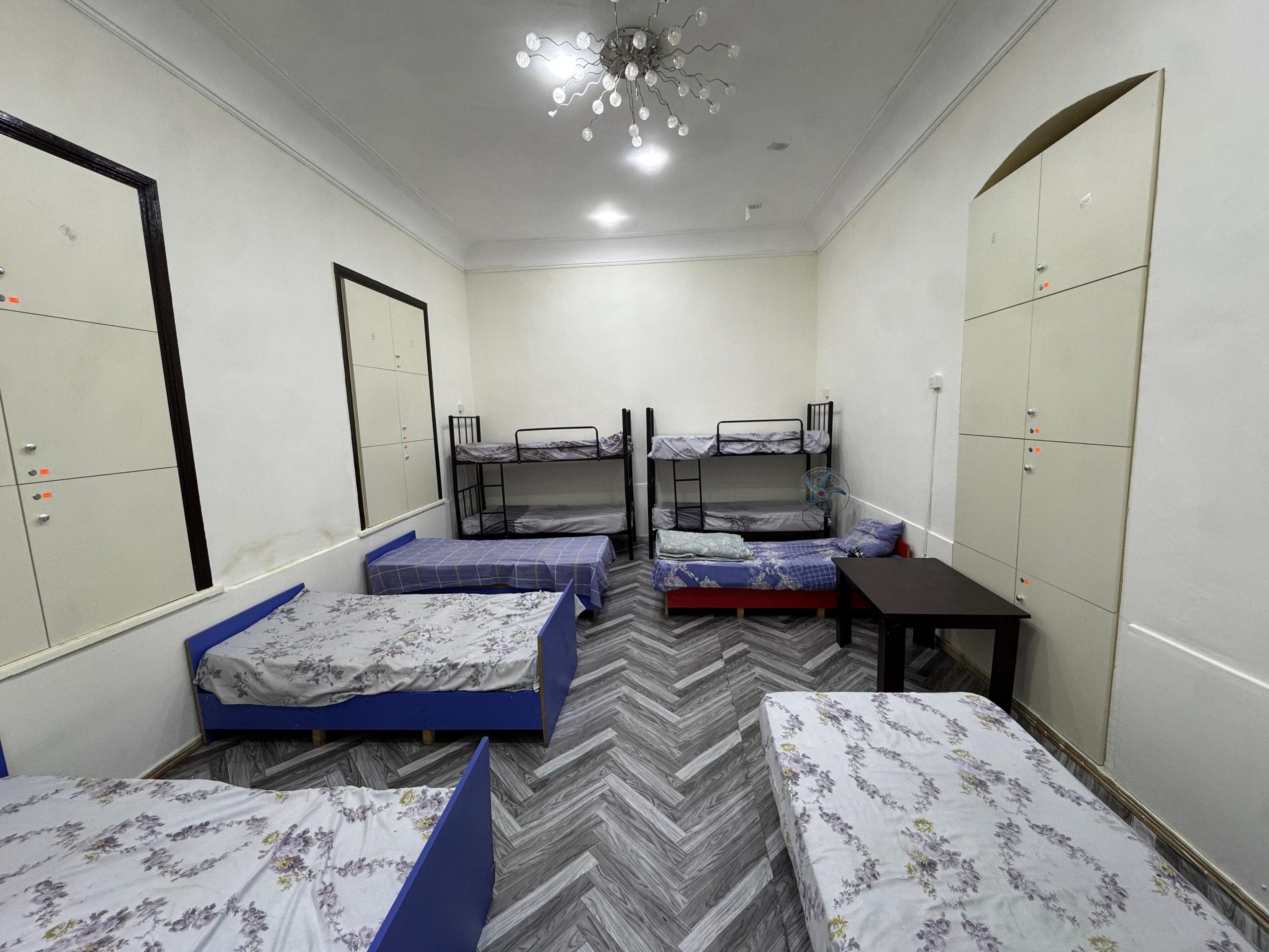 A dormitory room with bunk beds, a desk, and a wardrobe.