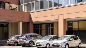 Ein modernes Gebäude mit Glasfassade und einem Parkplatz mit mehreren Autos.