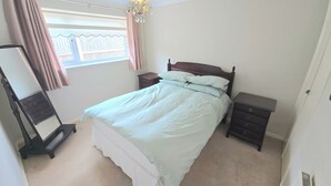 A bedroom with a bed, a dresser, a nightstand, a mirror, and a window with curtains. - Herne Bay - House - Sleeps 7 - Parking (Herne Bay)
