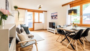 Una sala de estar moderna con sofá, televisor, mesa de comedor y sillas.