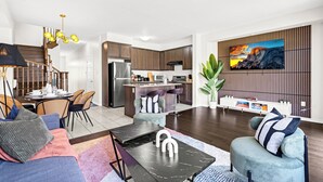 Een moderne woonkamer met een eethoek, keuken en trap.