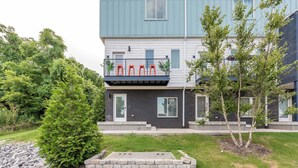 A modern two-story building with a balcony and a small garden area.