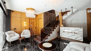 Ein moderner Empfangsbereich mit einem Marmor-Empfangstresen, einer Treppe und zwei weißen Sesseln.