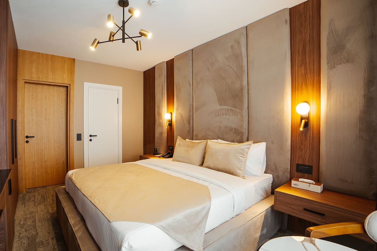 Ein Hotelzimmer mit einem großen Bett, Holzwandverkleidung, einem Schreibtisch und einem Sessel.
