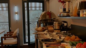 Eine Küche mit Buffetausstattung, ein Essbereich mit Stühlen und Blick durch Glastüren.