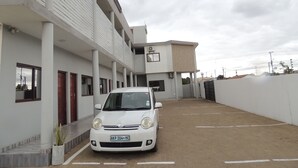 A white car parked in a building's parking lot. - 4040 Accomodation (Matola)