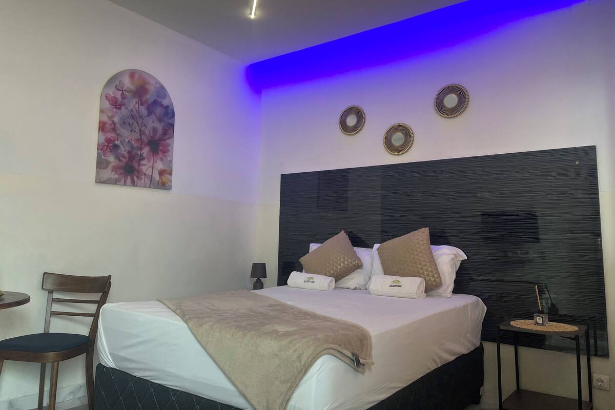 Ein Hotelzimmer mit einem Bett, einem Sessel, einem kleinen Tisch und einer Wand mit Dekorationen.