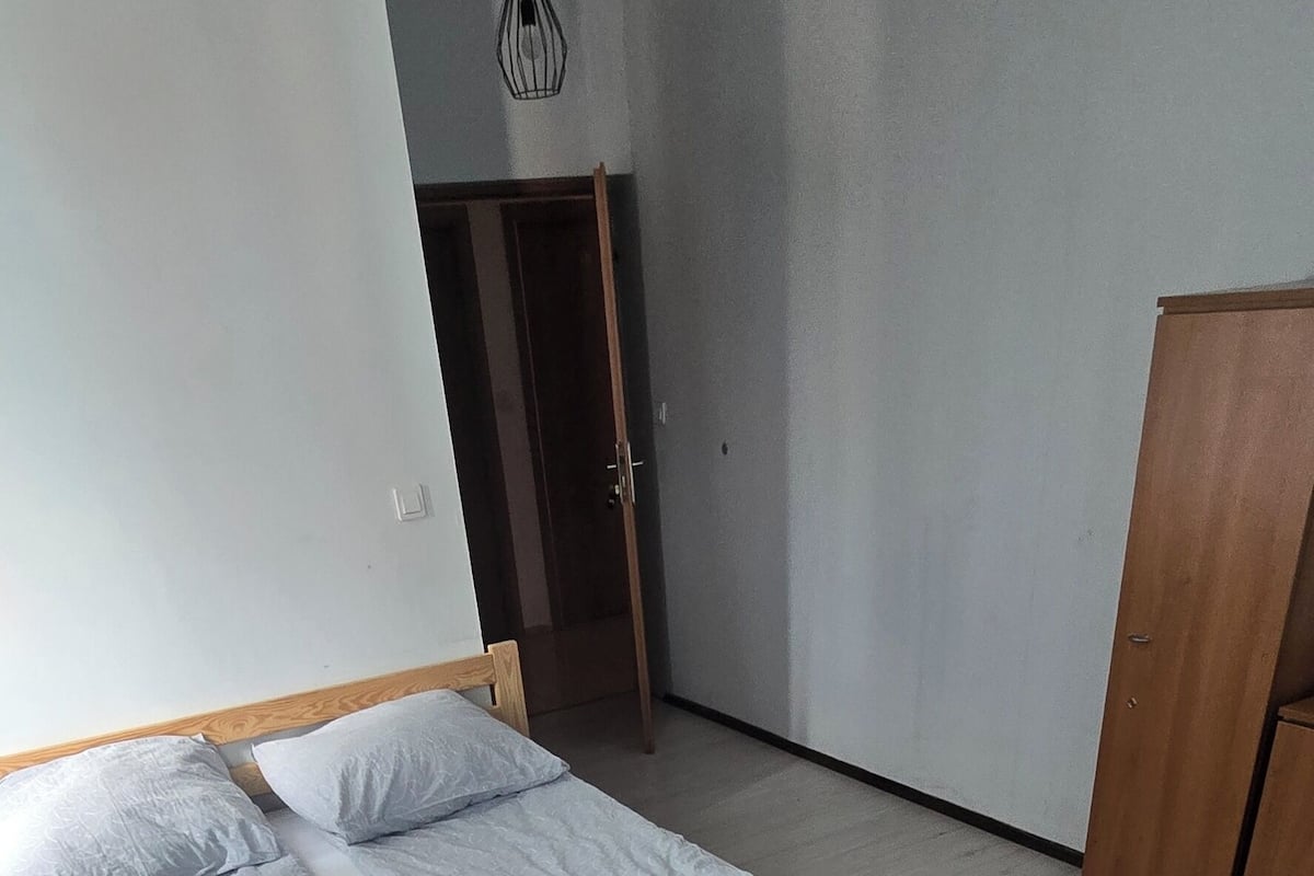 Una habitación con cama, armario de madera y una puerta.