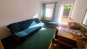 Ein Zimmer mit einem Bett, einem kleinen Tisch mit Tablett und einem Fenster mit Vorhängen.
