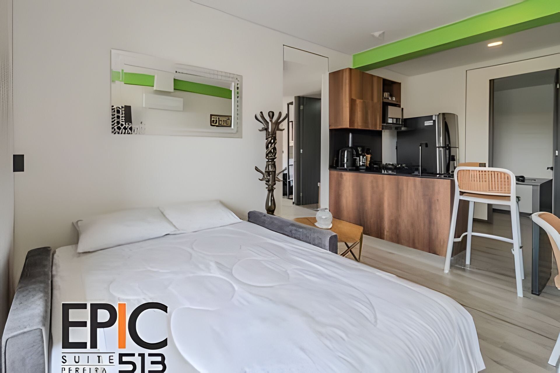 Una habitación de hotel moderna con una cama grande, una kitchenette y un comedor.