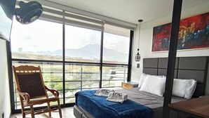 Un dormitorio moderno con una cama grande, un sillón mecedora y vistas a las montañas a través de amplios ventanales.