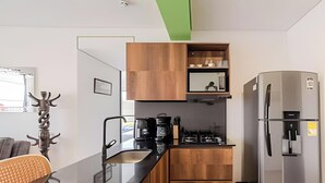 Una cocina compacta con armarios de madera, una cafetera y un refrigerador.