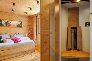 Ein Zimmer mit Holzwänden, einem Bett, einem Gemälde und einer Dusche.