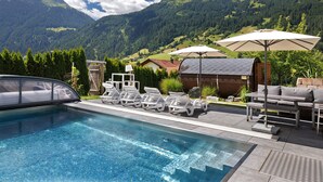 A pool area with lounge chairs, umbrellas, and a view of mountains.
