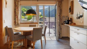 A modern kitchen with a dining area, large windows, and a view of mountains.