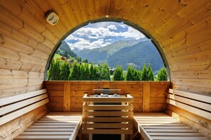 A sauna with a wooden interior, a bench, and a view of mountains and greenery. - Apartment 'Toni' with Mountain View, Private Terrace and Wi-Fi (Gaschurn)