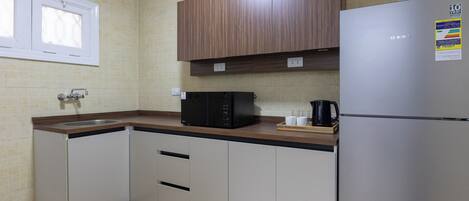 A kitchen with a stainless steel refrigerator, a microwave, and a coffee maker on the counter.