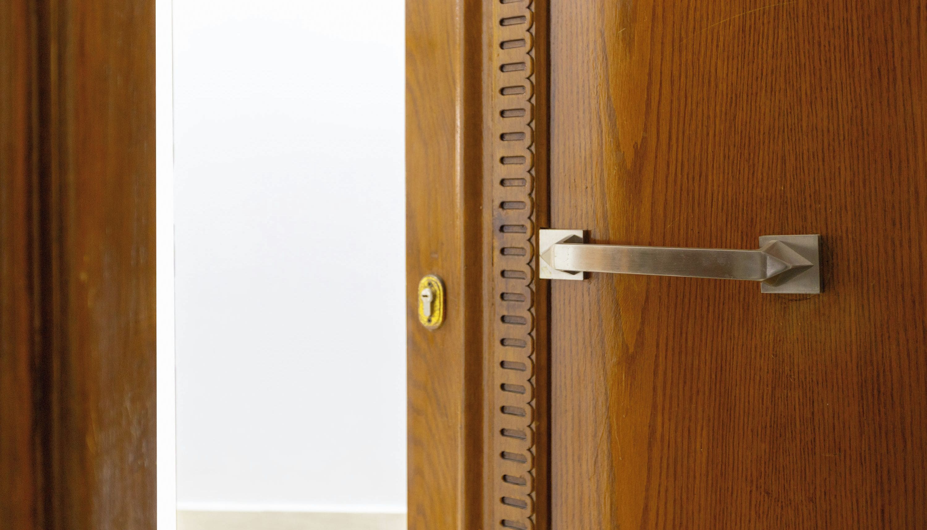 A wooden door with a metal latch and a keyhole.