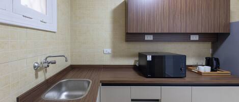 A kitchen with a sink, a microwave, and cabinets.