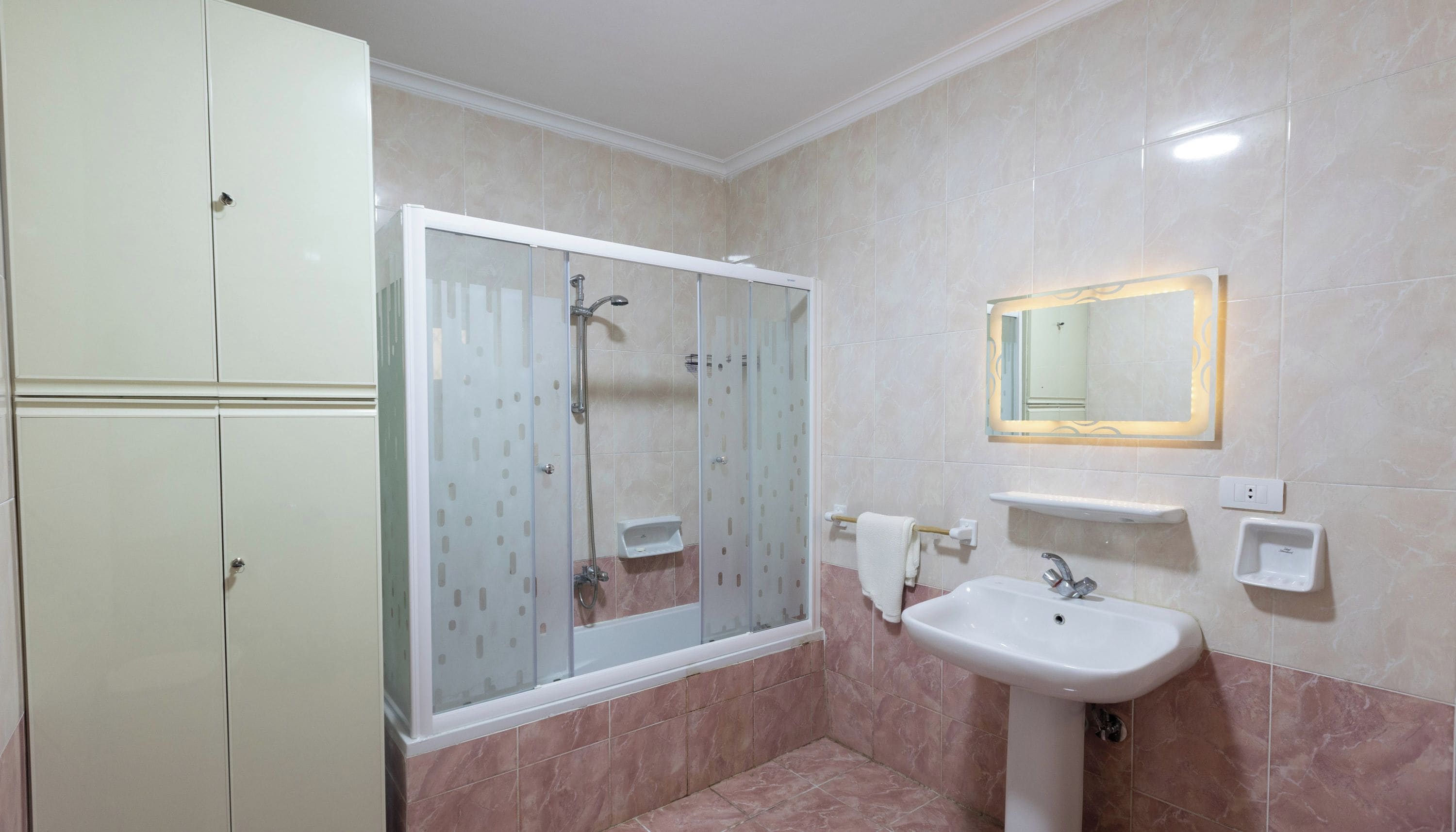 Une salle de bain avec une douche, un lavabo, un miroir et un meuble de rangement.