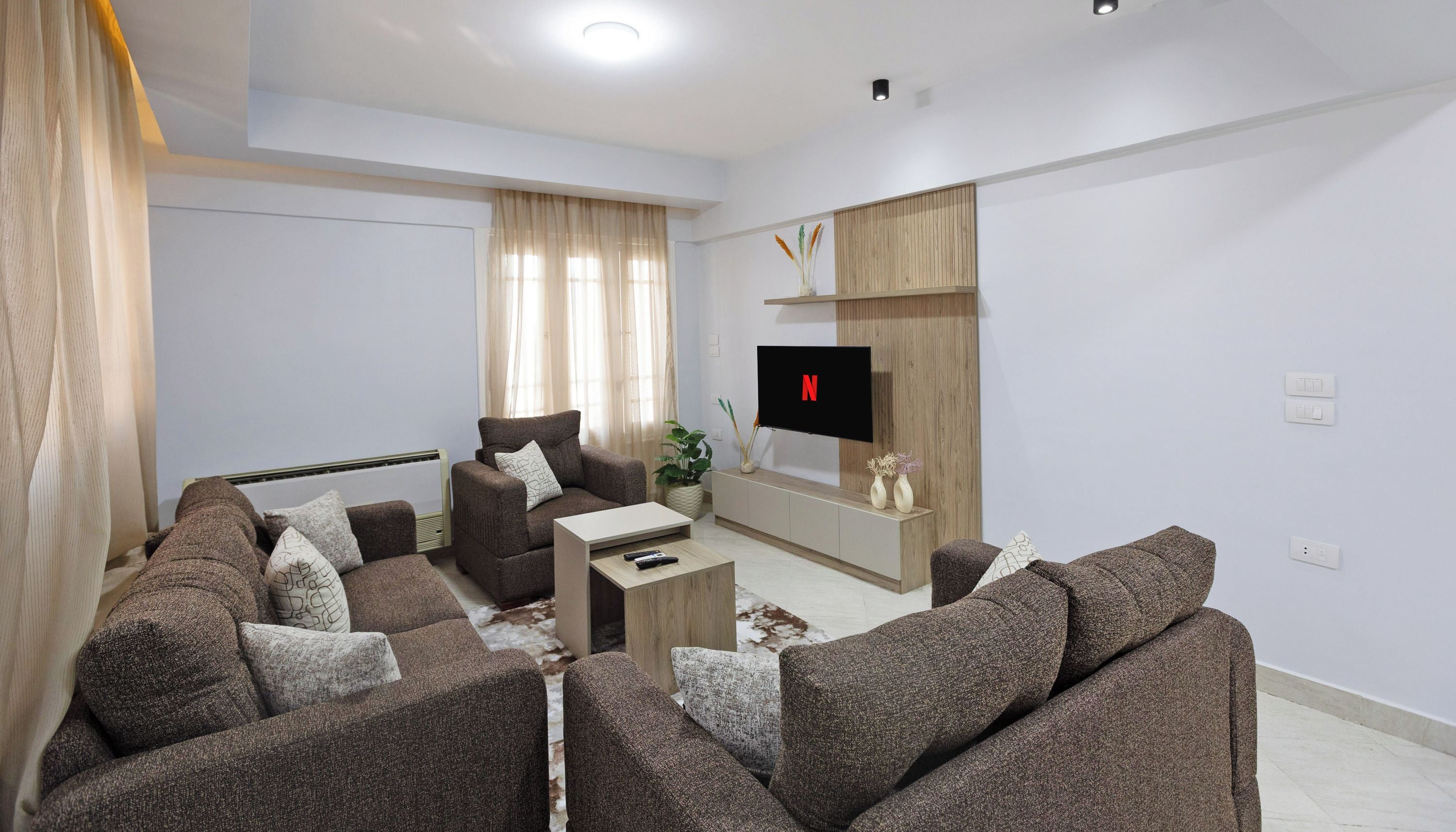 A modern living room with a sofa set, a coffee table, and a TV mounted on the wall.