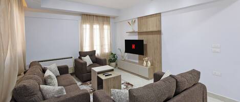 A modern living room with a sofa set, a coffee table, and a TV mounted on the wall.