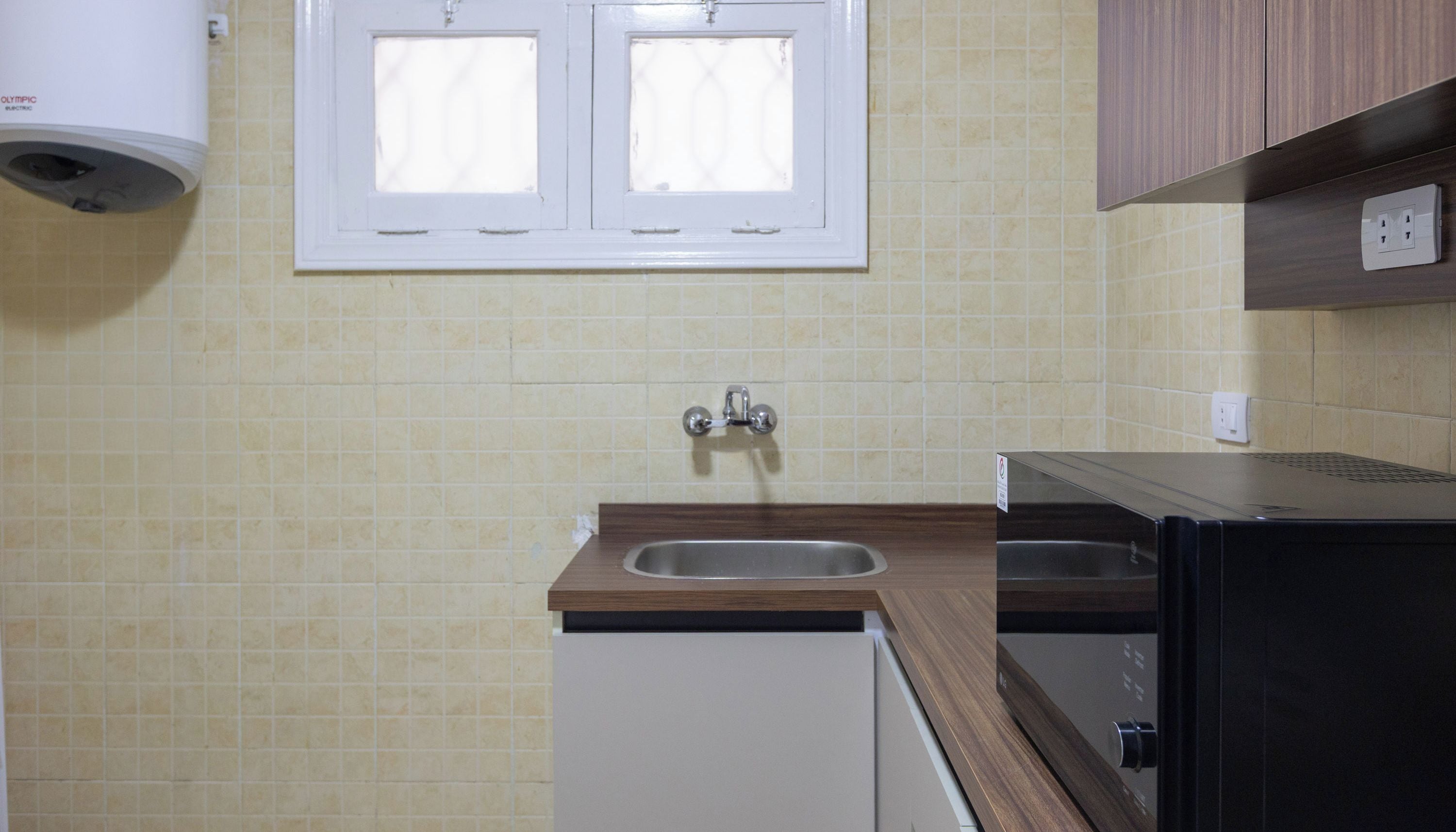 Una cocina con ventana, un lavamanos y un microondas.