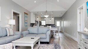 A modern living room with a grey sofa, a white coffee table, and a patterned rug.