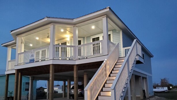 A two-story house with a covered porch and a staircase leading to the upper level.