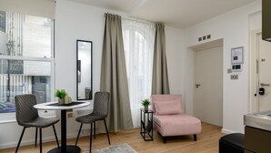 En moderne stue med et rundt bord, to stole, en lyserød sofa og et lille sofabord med en plante.