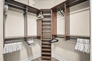 A walk-in closet with wooden shelving, a central staircase, and hanging storage for clothes. - Esplanade Hacienda 3BR/2BA Pet Friendly Resort Amenities Near Beaches (Naples)