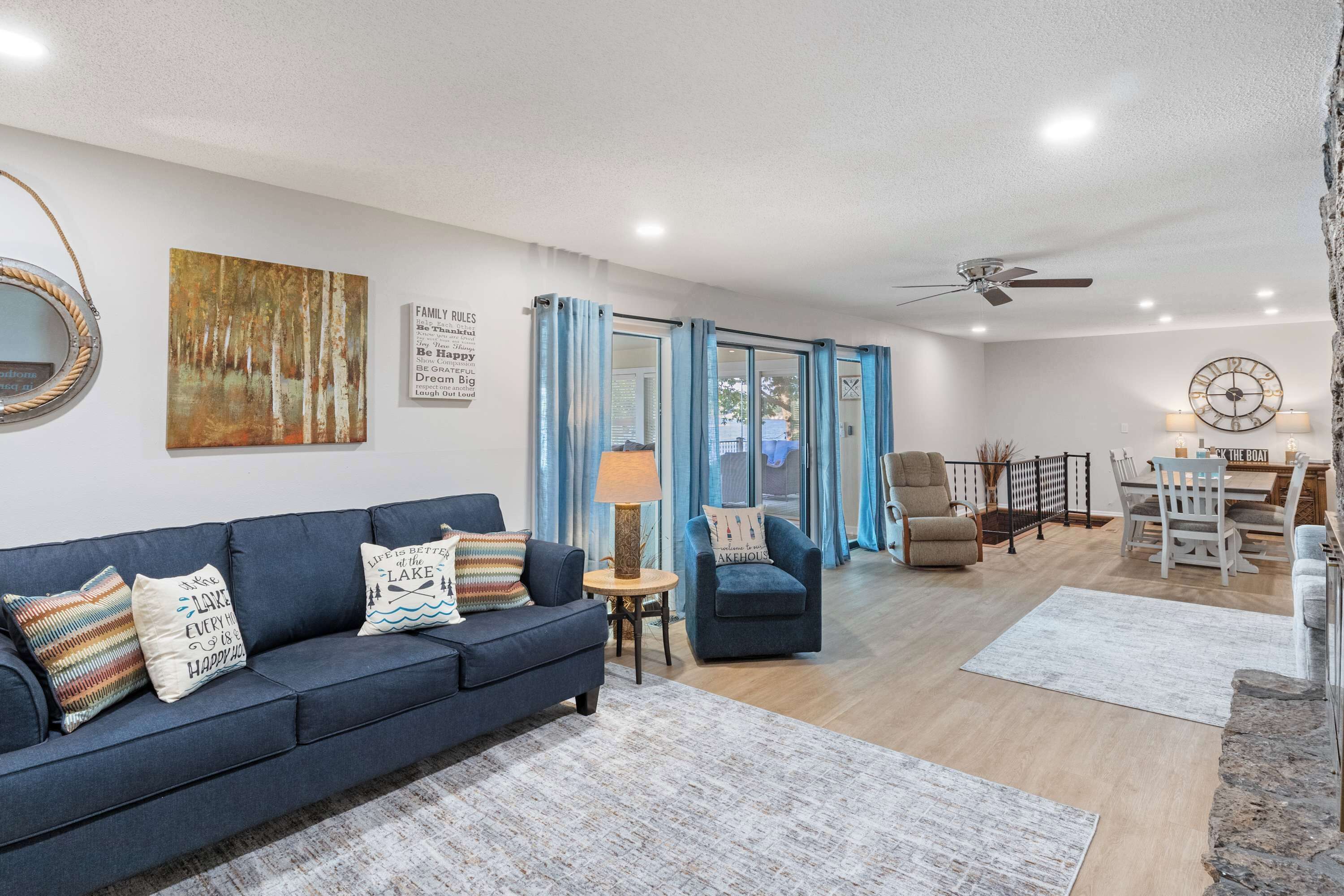 A living room with a sofa, armchairs, a dining table, and a kitchen area.